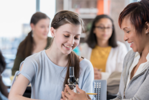 IB student and teacher with microscope